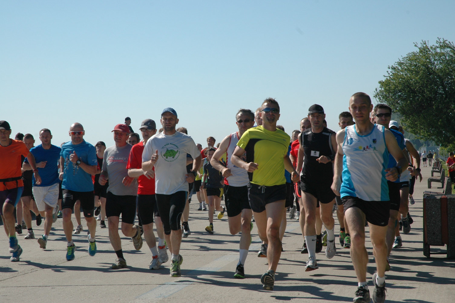 grafika przedstawiająca biegnących ludzi w słoneczny dzień