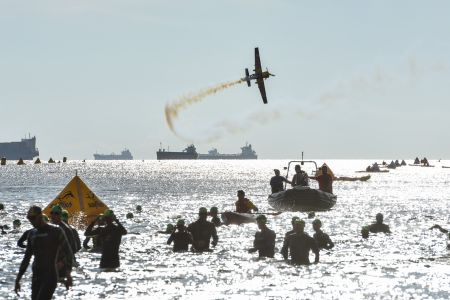 zawodnicy podczas rozgrzewki w wodzie. w tle na niebie samolot