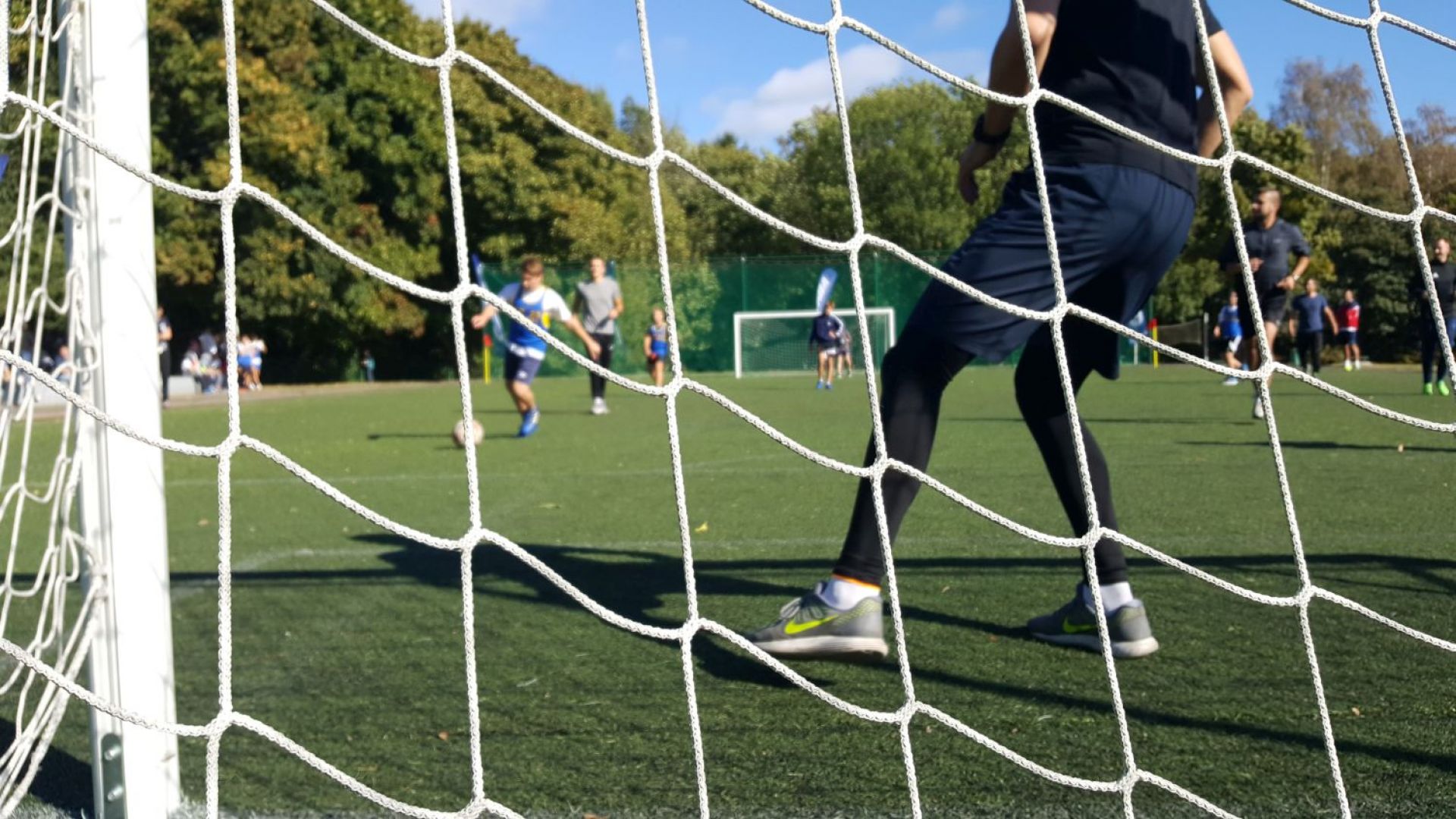 Sport szkolny - zdjęcie boiska z grającymi chłopcami zrobione od tyłu bramki