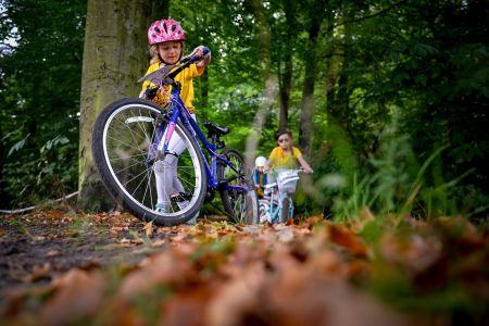 Dziewczynka pchająca rower w lesie