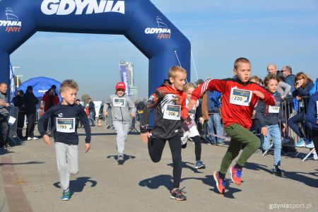biegnący chłopcy w tle kibice i granatowa brama z napisem Gdynia