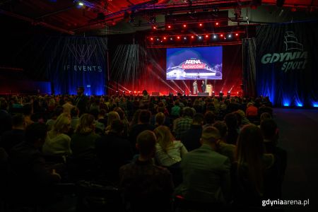 Zdjęcie z Areny Mówców w Gdynia Arenie w 2019 - ciemna sala pełna ludzi z prelegentem i podczas prezentacji