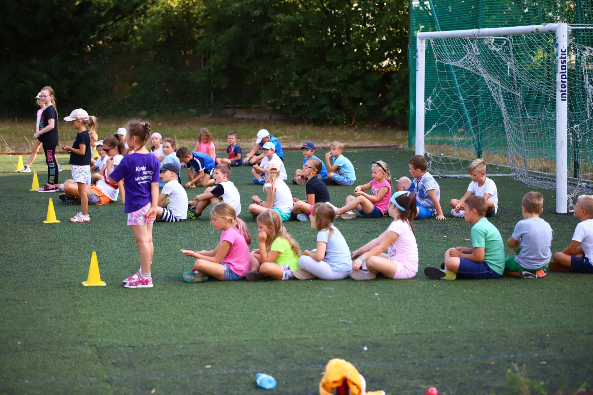 Dzieci siedzące na boisku sportowym