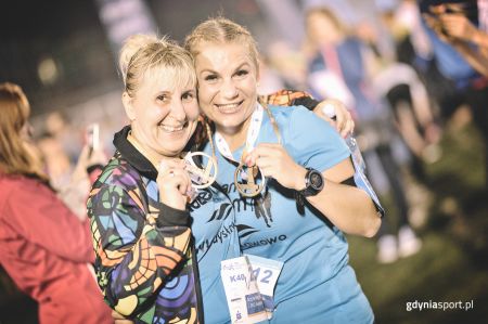 Usmiechnięte kobiety z medalami biegowymi