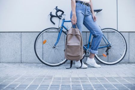 kobieta stojąca na tle roweru z plecakiem