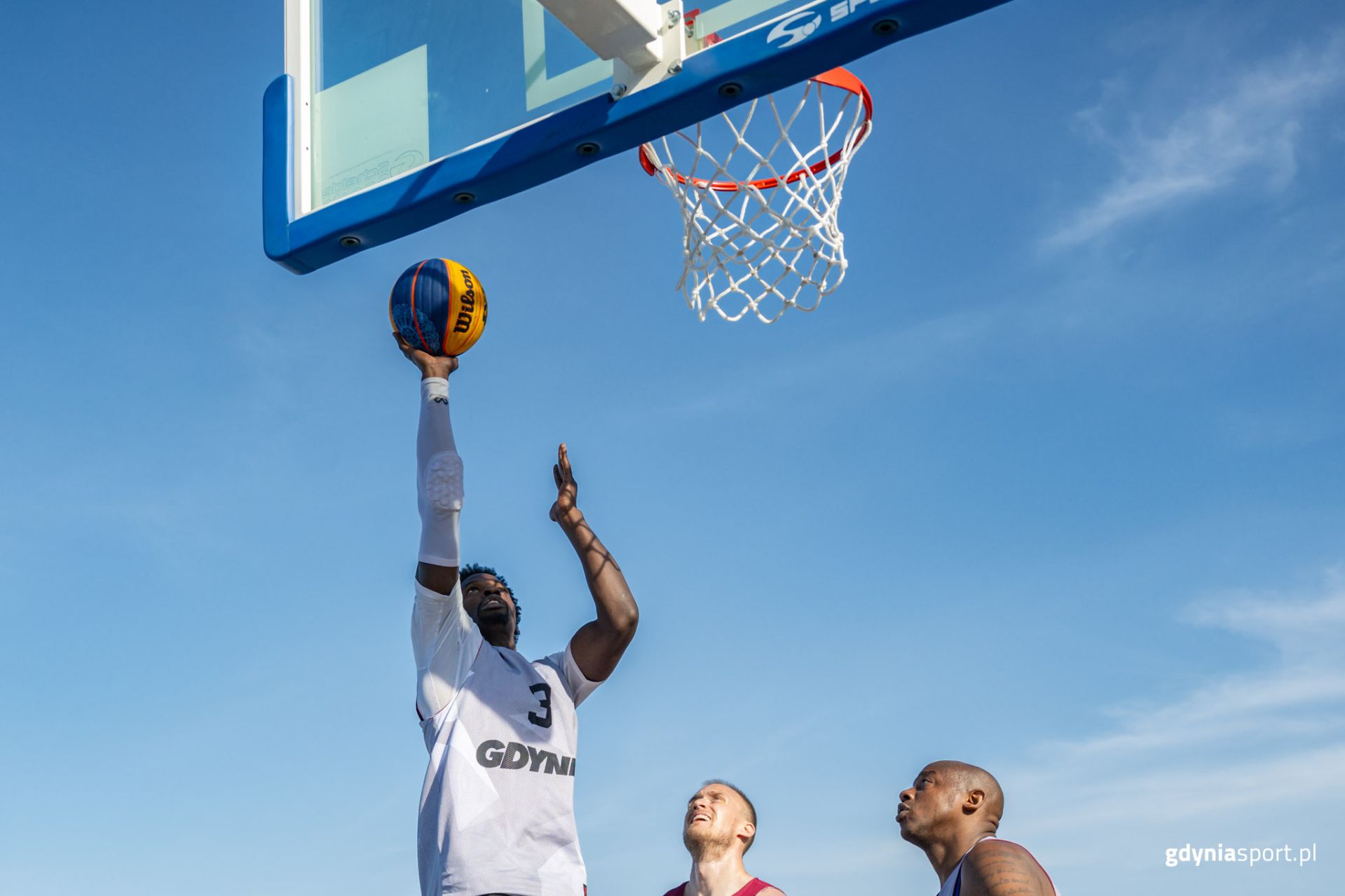 zawodnik rzucający do kosza na tle nieba